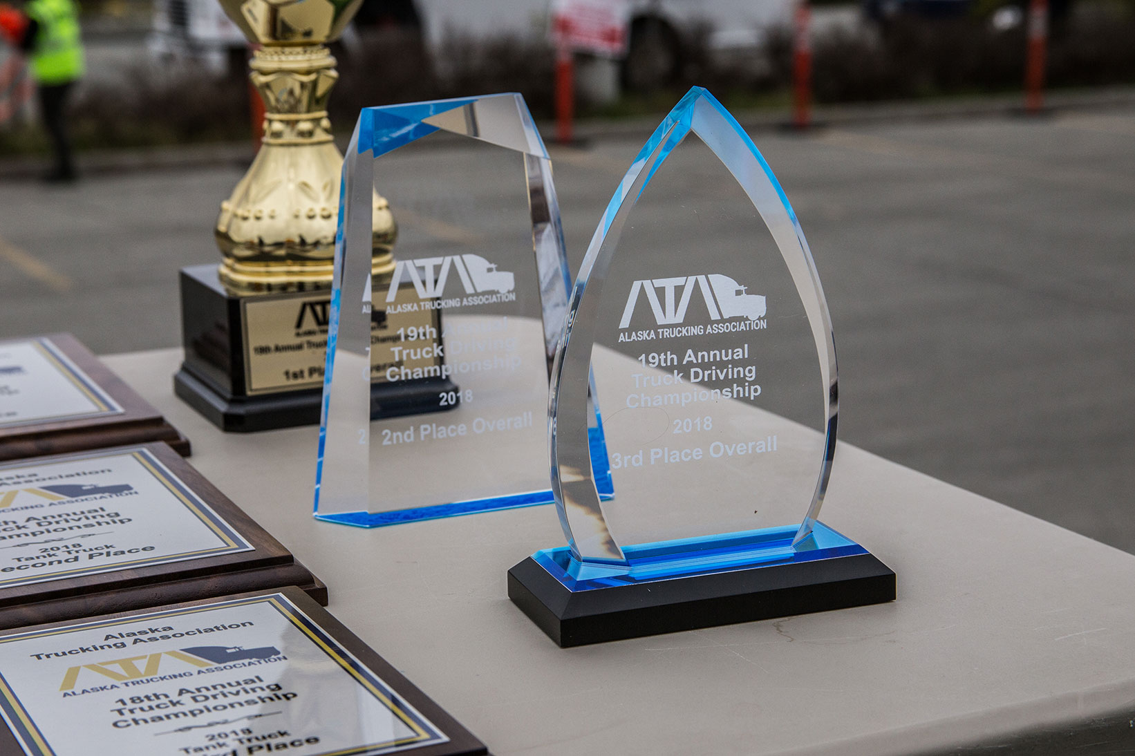 Two awards are sitting on a table with other trophies.