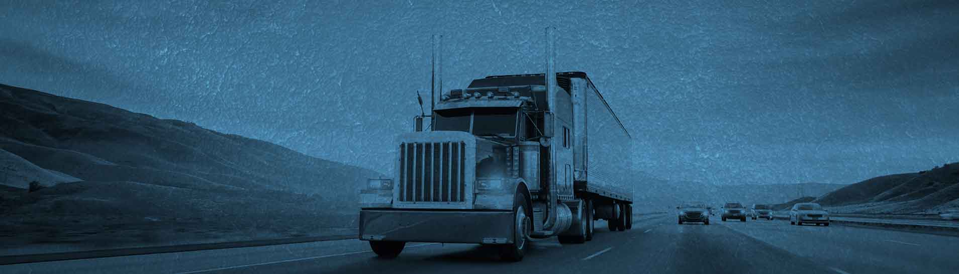 A semi truck is driving down the street.