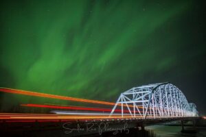 Bridge under green northern lights sky.